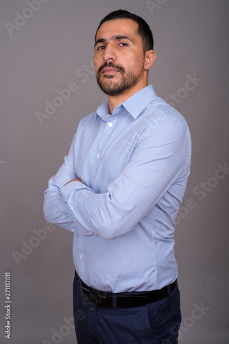 Handsome bearded Persian businessman against gray background