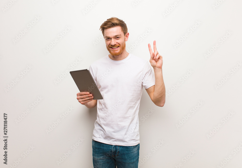 Young redhead man showing number two. Holding a tablet. Young redhead man showing number two. Holding a tablet.