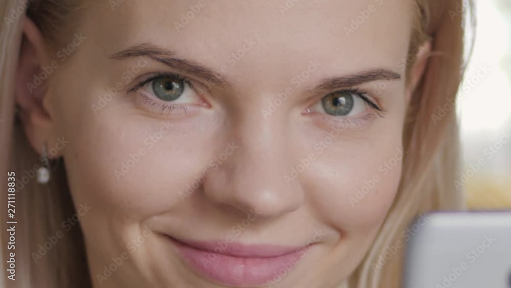 Extreme closeup shot of happy fresh looking face young caucasian blonde woman using smartphone. Young attractive girl indoors using social networking app, scrolling, typing, swiping on touchscreen Extreme closeup shot of happy fresh looking face young caucasian blonde woman using smartphone. Young attractive girl indoors using social networking app, scrolling, typing, swiping on touchscreen