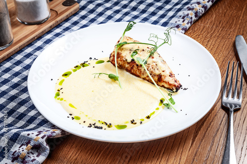 Close up view on served chicken fillet with polenta and corn sauce on wooden background. Modern cuisine. Copy space. Picture for recipe or menu