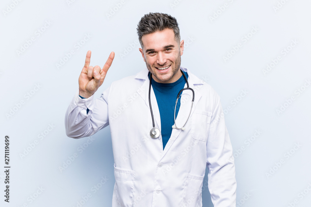 Young handsome doctor man showing a horns gesture as a revolution concept. Young handsome doctor man showing a horns gesture as a revolution concept.