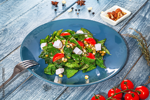 Fresh green vegan salad served in blue plate on blue wooden background with ingridents. spinach, chickpea, cheese. Healthy food concept. Copy space. Green vegan meal in bowl. Clean eating, dieting photo