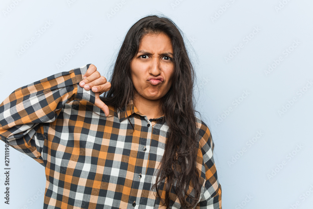 Young cool indian woman showing a dislike gesture, thumbs down. Disagreement concept. Young cool indian woman showing a dislike gesture, thumbs down. Disagreement concept.