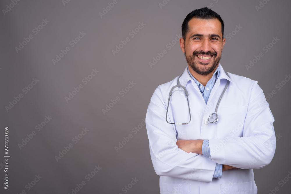 Handsome bearded Persian man doctor against gray background Handsome bearded Persian man doctor against gray background