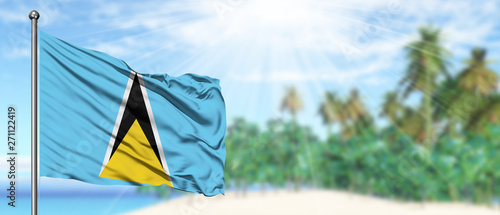Waving Saint Lucia flag in the sunny blue sky with summer beach background. Vacation theme, holiday concept.