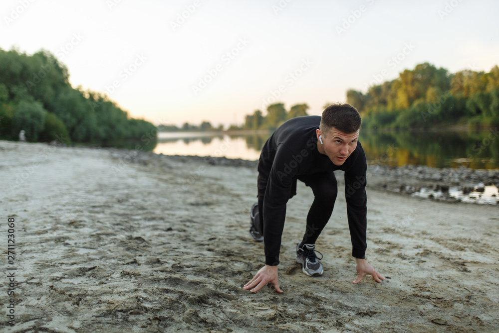 Young sportsman is about to start running on the beach