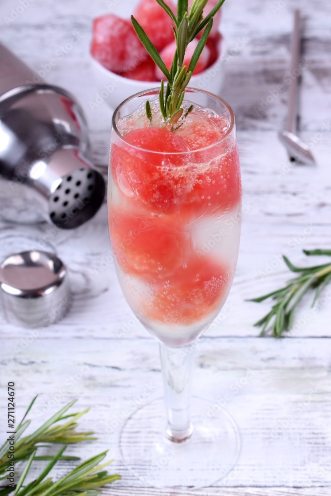 Sparkling cocktail with watermelon balls and rosemary in a champagne glass Sparkling cocktail with watermelon balls and rosemary in a champagne glass
