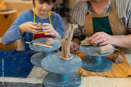 Pupil and his art teacher sculpting little clay giraffe photo