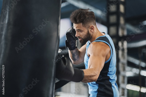 Active guy punching boxing bag at gym © Prostock-studio