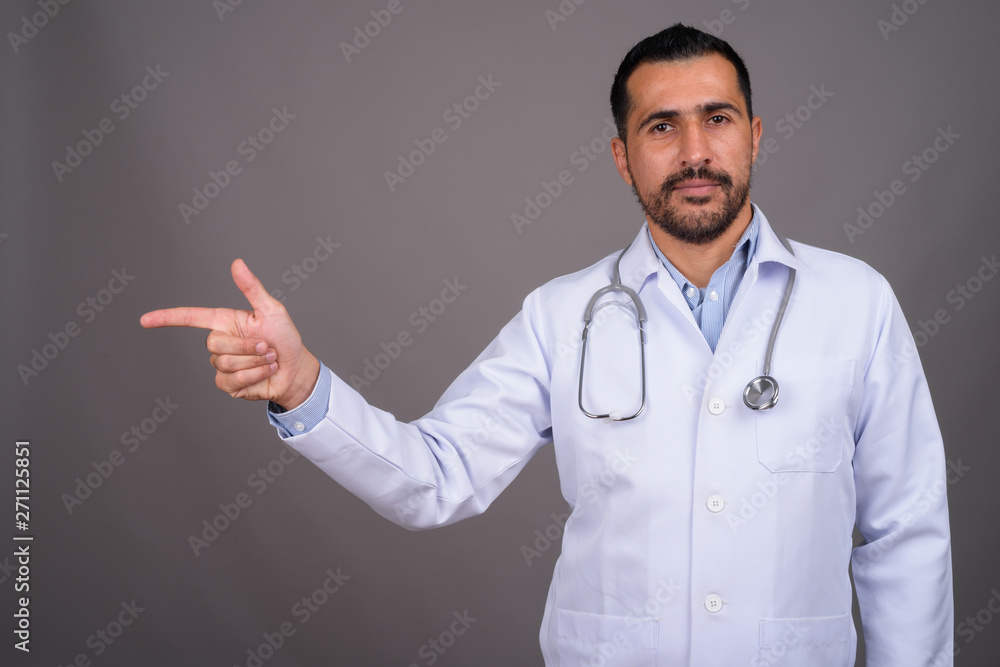 Handsome bearded Persian man doctor against gray background Handsome bearded Persian man doctor against gray background