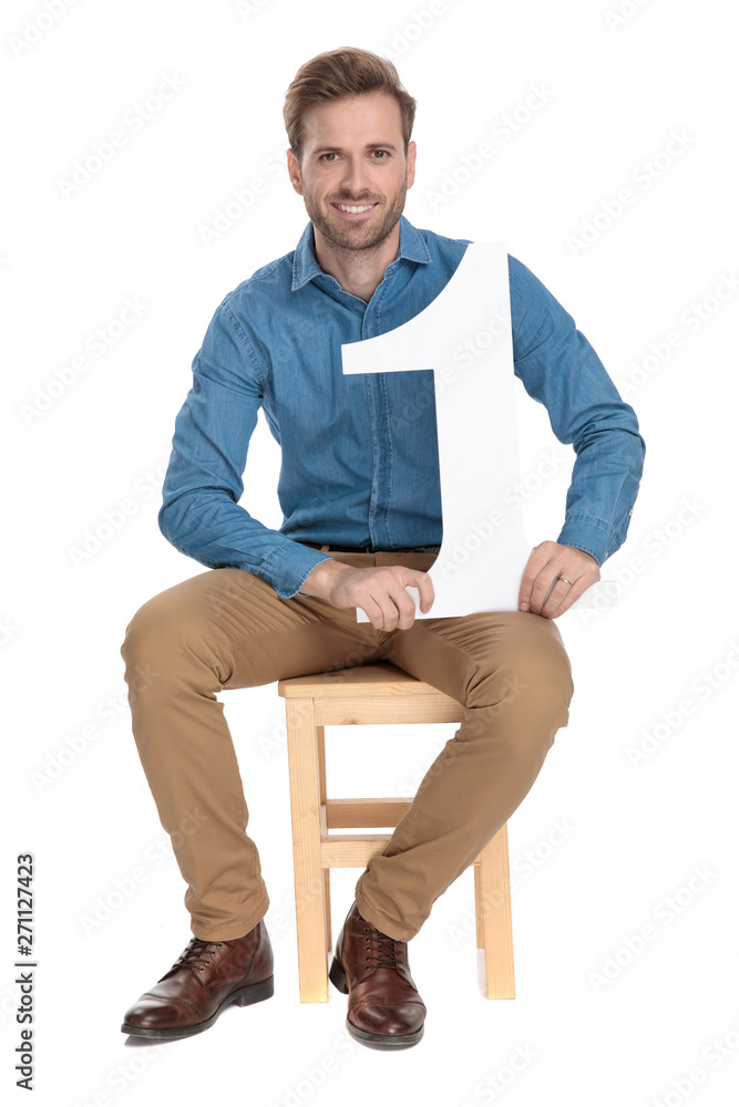 Positive man sitting and holding a number one maquette