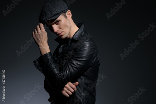 Tough young man adjusting his hat and frowning
