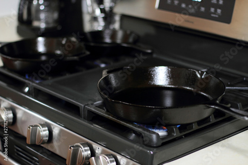 Cast iron skillets heating up on a natural gas stove.