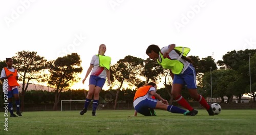 Female soccer player tackling down another player on soccer field.