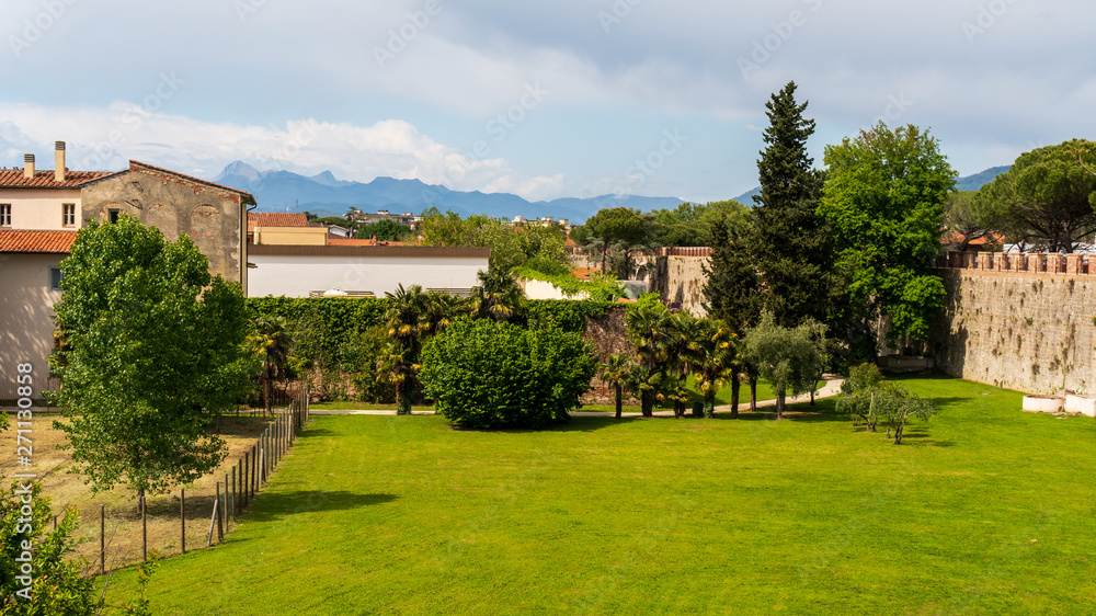 View from the scenic Ancient Walls of Pisa, one of the famous Italian landmarks, over a nearby park on a sunny summer day in Italy. 