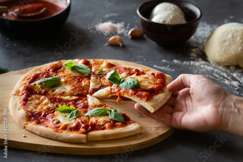 Ingredients for traditional Italian pizza Margherita with tomato sauce, Mozzarella cheese, basil on a dark concrete background. Pizza recipe and menu.