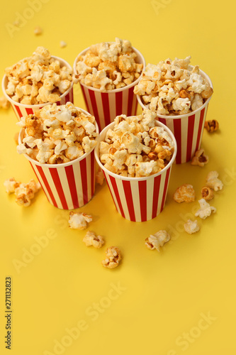 five red-and-white paper cups with popcorn on a yellow backgroun