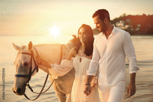Young couple walking a majestic horse - seaside landscape © konradbak