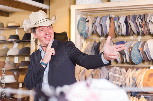 happy adult male try on western hat at the shopping center
