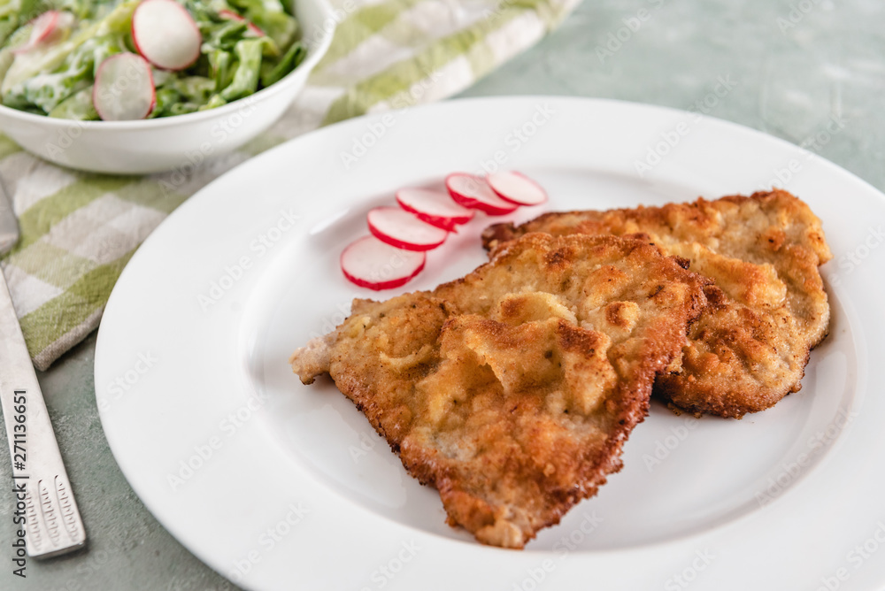 Fried pork chop in breadcrumbs served with radishes and lettuce. Fried pork chop in breadcrumbs served with radishes and lettuce.
