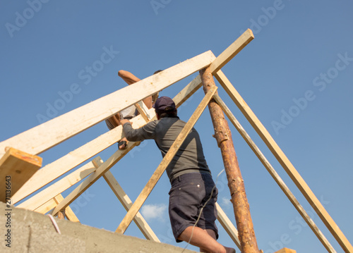Roofer, carpenter on the roof, he closes the roof of a small and cozy house