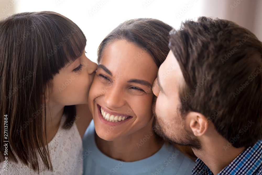 Loving dad and daughter kiss smiling mom on cheeks Loving dad and daughter kiss smiling mom on cheeks