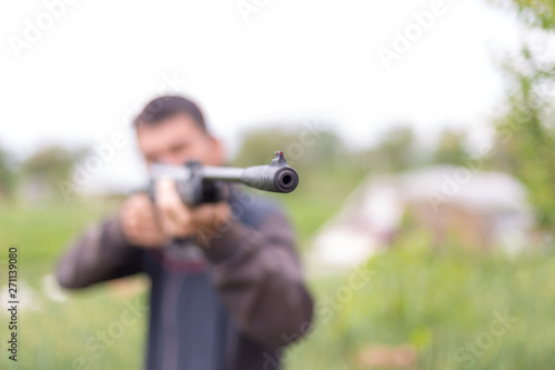 Young man shoots air rifle in nature