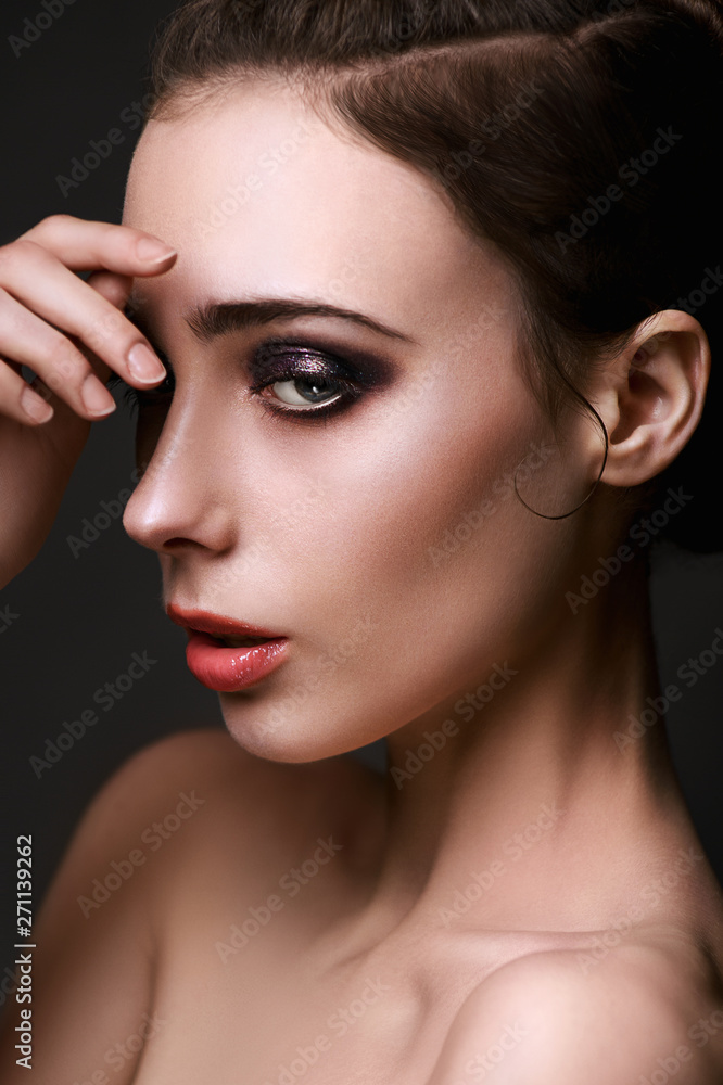 Fototapeta premium Beautiful brunette with bright make-up smoky eyes, thick eyebrows, pink lips. Evening look