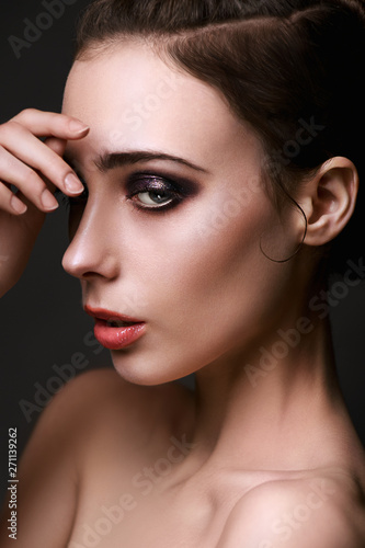 Beautiful brunette with bright make-up smoky eyes, thick eyebrows, pink lips. Evening look