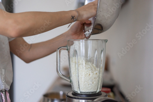 Woman pouring cottage cheese into a blender in the kitchen