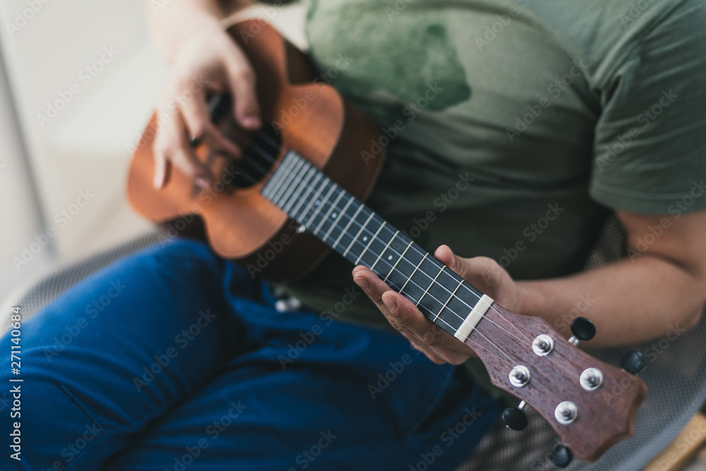 ukulele game. a man playing a little guitar. the performer writes the music on the ukulele at home.
