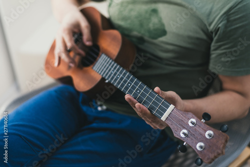 ukulele game. a man playing a little guitar. the performer writes the music on the ukulele at home.