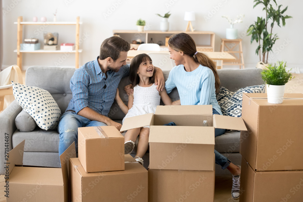 Excited parents relax on sofa with daughter on moving day Excited parents relax on sofa with daughter on moving day