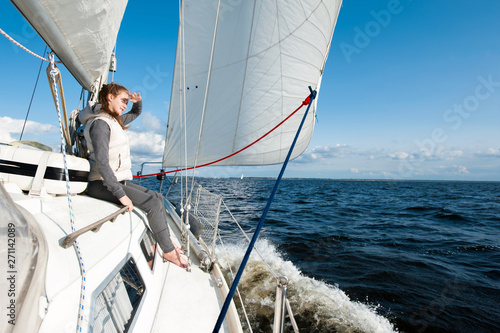 Young girl looking forward sitting on yacht desk having trip