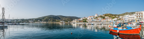 View of Batsi, a traditional village at the island of Andros, with a beautiful red fishing boat on the forground, Cyclades, Greece