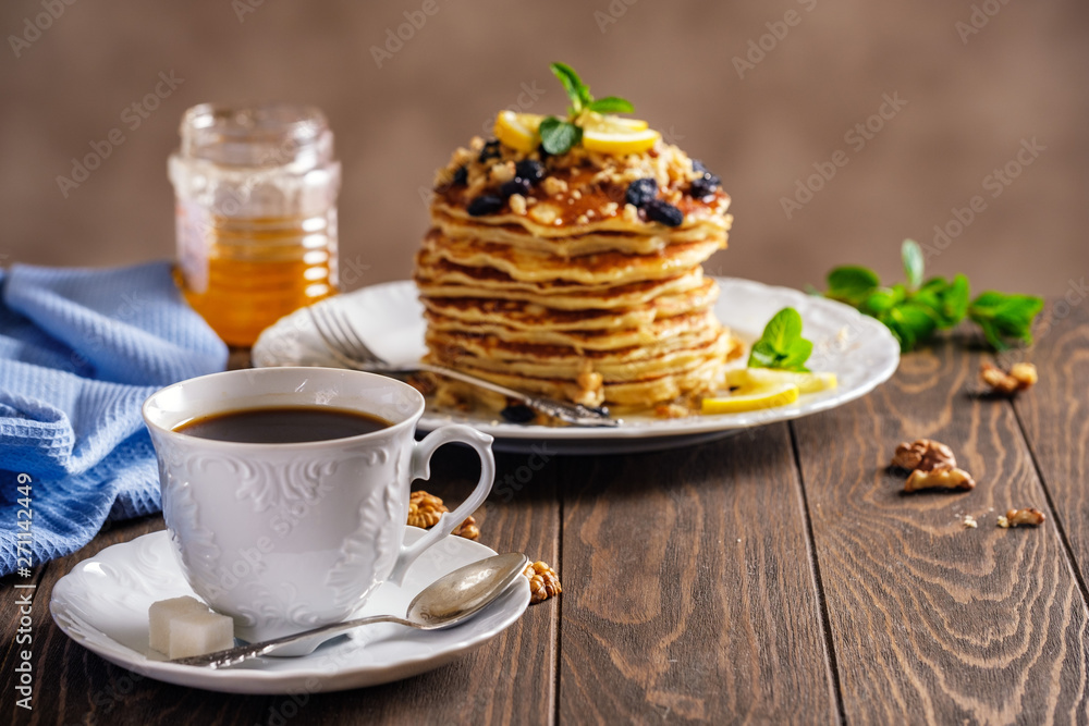 Pancakes with honey, nuts and raisins with a cup of coffee Pancakes with honey, nuts and raisins with a cup of coffee