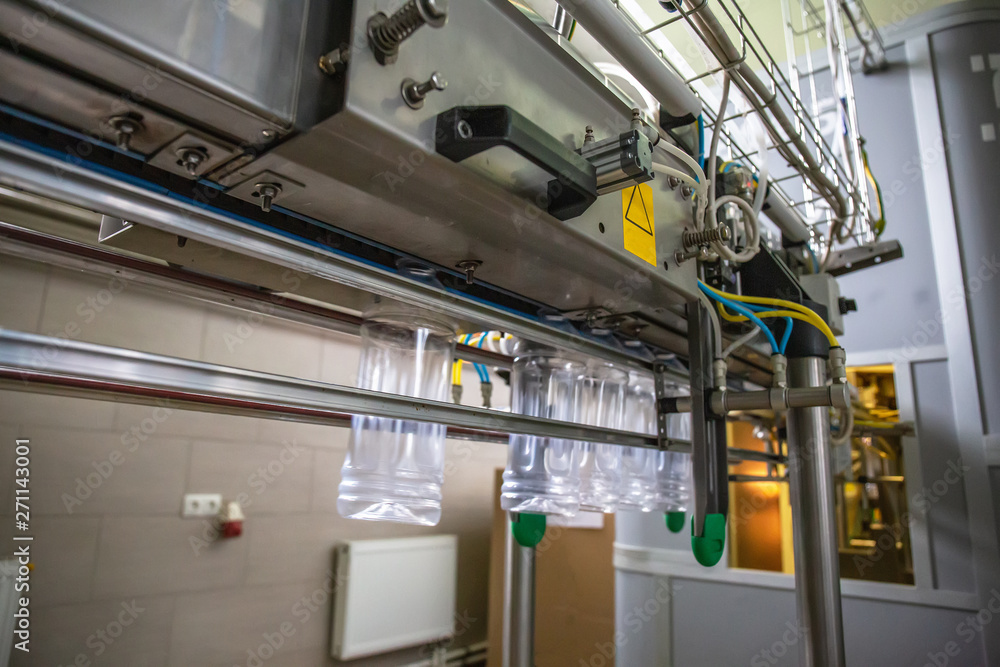 Industrial automated machine for blowing plastic bottles from PET preforms, conveyor belt in plant Industrial automated machine for blowing plastic bottles from PET preforms, conveyor belt in plant