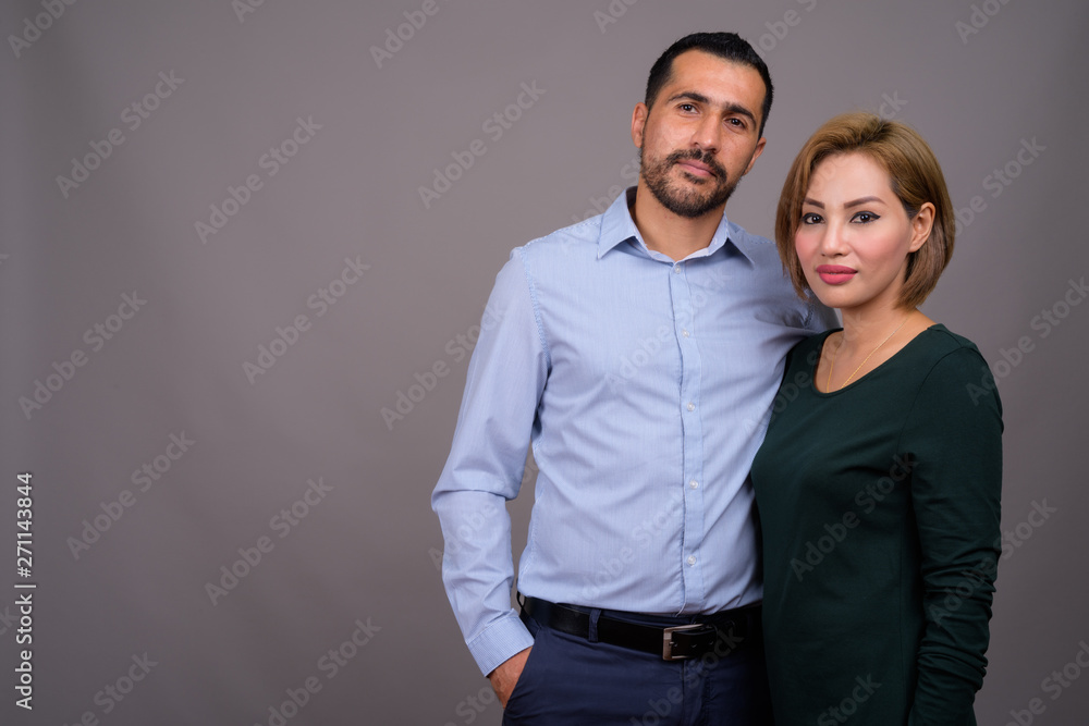 Multi-ethnic couple in love against gray background Multi-ethnic couple in love against gray background