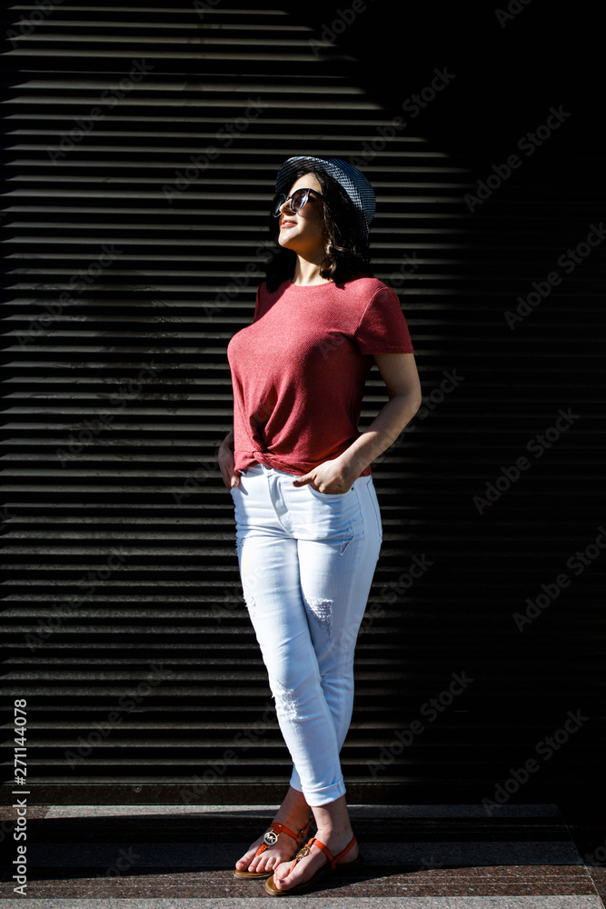Young pretty brunette walking around the city on a sunny day, dressed in summer clothes, and a hat on her head. Summer style Young pretty brunette walking around the city on a sunny day, dressed in summer clothes, and a hat on her head. Summer style