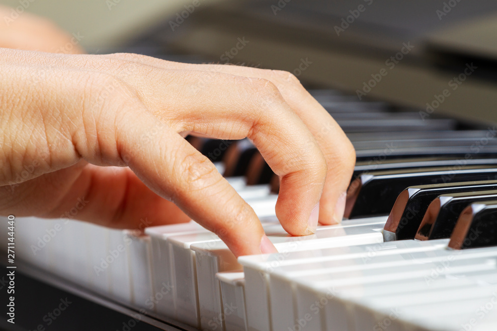 Obraz premium Close up view of kid hands playing on piano keyboard