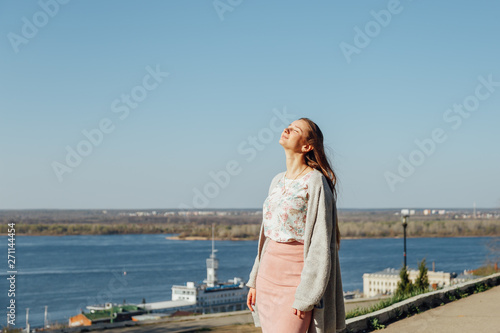 Calm beautiful smiling young woman enjoying fresh air outdoor, relaxing with eyes closed, feeling alive, breathing, dreaming. Side view portrait