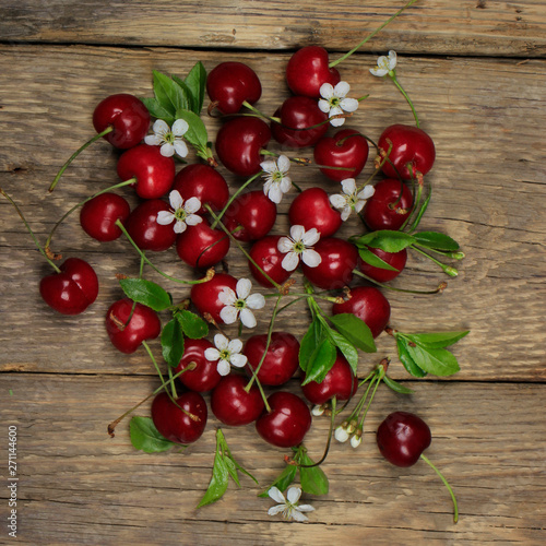 heap of cherry with leaves and flowers on wooden background