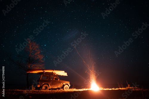 Night landscape with bright campfire and car