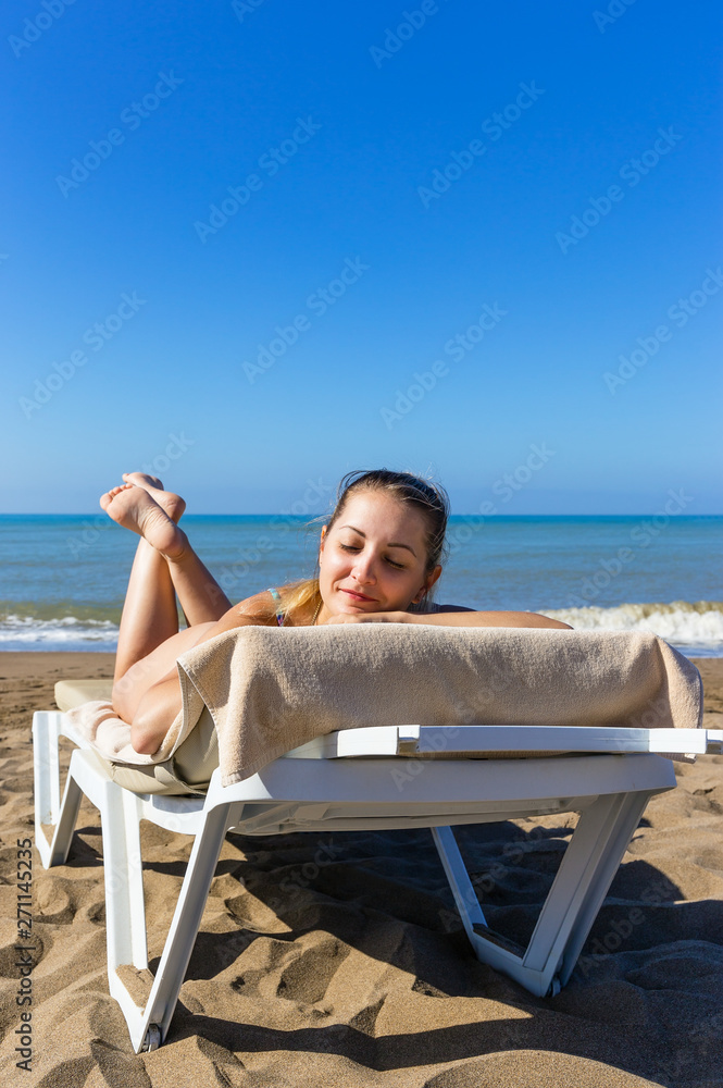 Cute girl sunbathes on beach by the sea