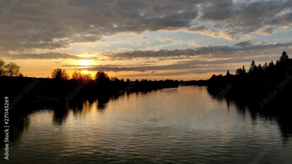Sunlight through the orange horizon during the evening in northern Europe in a river bank with sky full of clouds in 4K Sunlight through the orange horizon during the evening in northern Europe in a river bank with sky full of clouds in 4K