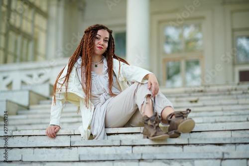 dreadlocks fashionable girl dressed in white posing on old palace background