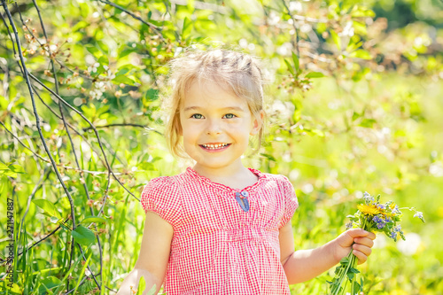 Happy little girl playing with bouquet in sunny park