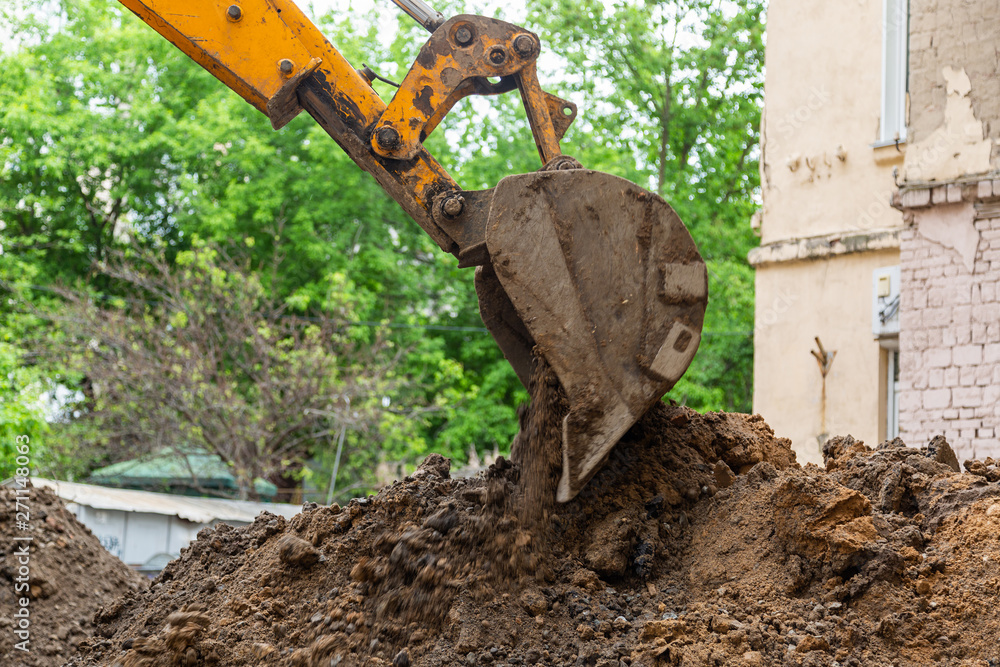 Excavator bucket pours ground. Repair work plumbing.