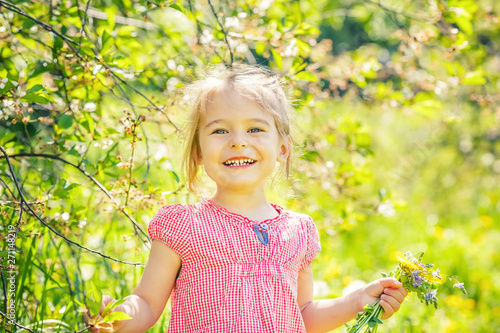 Happy little girl playing with bouquet in sunny park