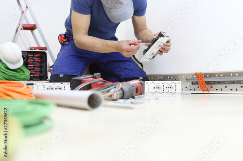 electrician at work with screwdriver in hand connects the cables to the socket, electrical wiring